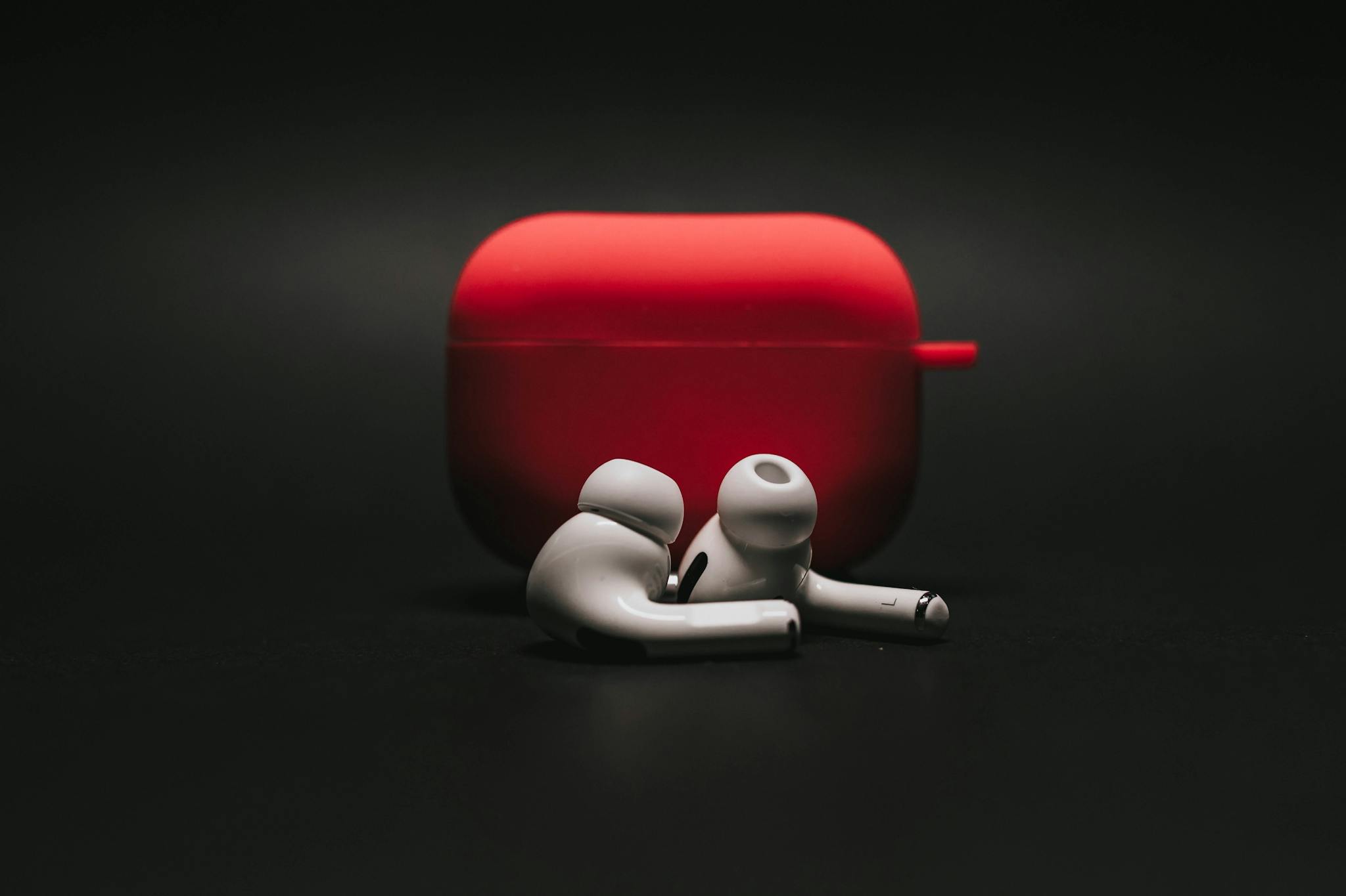 Albums 4 Sleek white earbuds with modern red case on a dark surface, highlighting stylish audio technology.